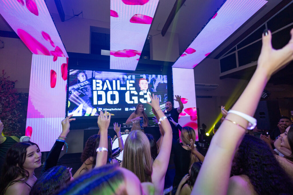 Convidados dançando diante do painel de LED com o nome da atração musical