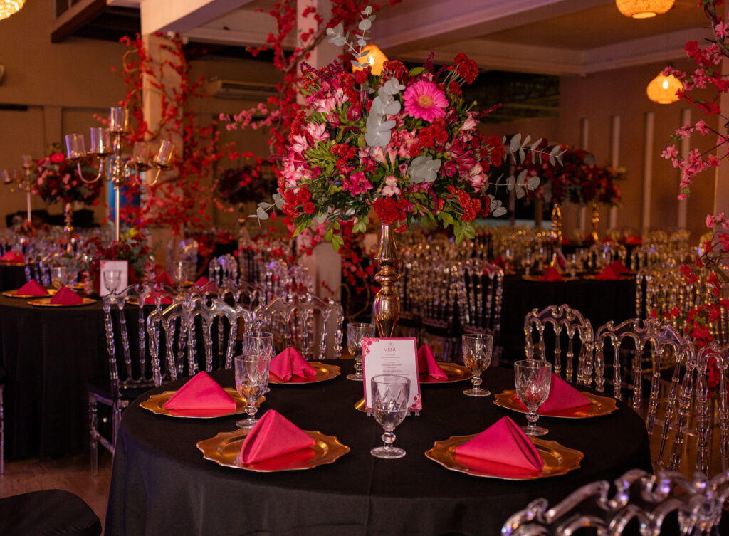 Mesa dos convidados com toalha preta, guardanapos vermelhos e candelabros de cristal