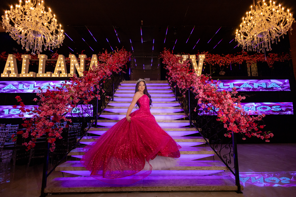 Salão da festa de 15 anos com escadaria central, lustres de cristal e letreiro luminoso