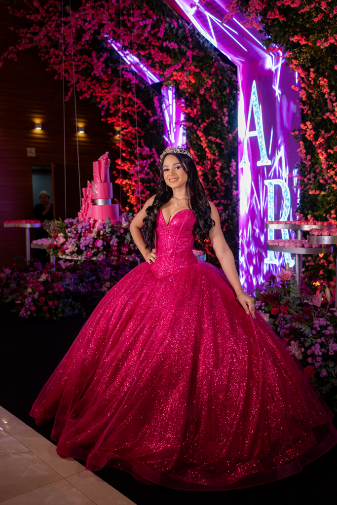Debutante em vestido pink diante da parede de flores e luzes neon