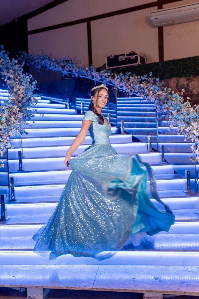 Debutante desce a escadaria com o vestido azul em movimento