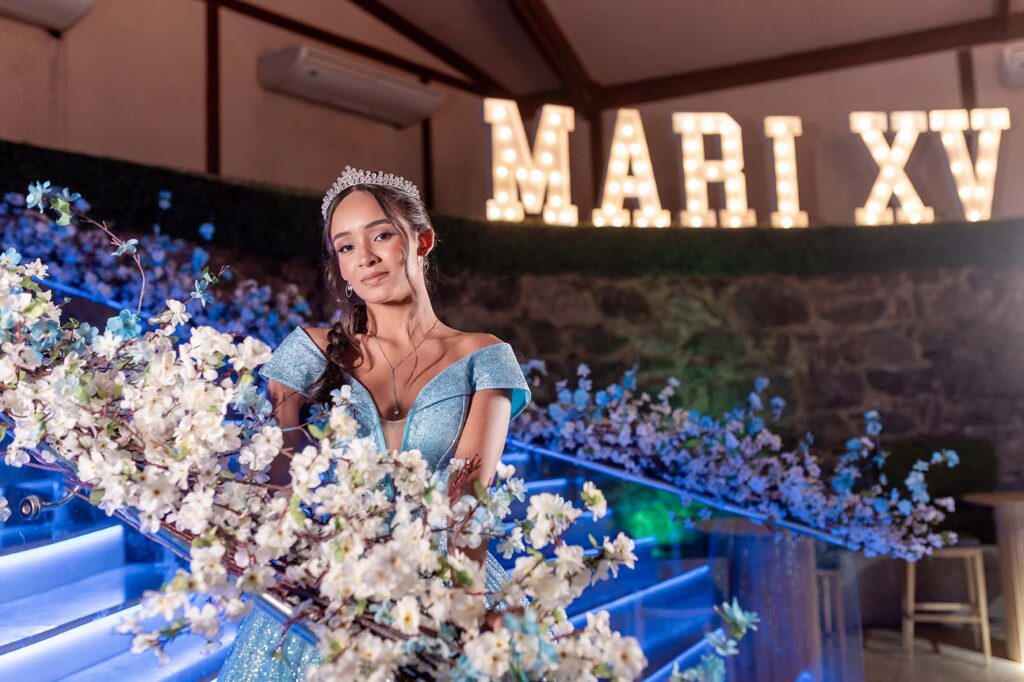 Debutante diante do letreiro luminoso entre as flores da escadaria