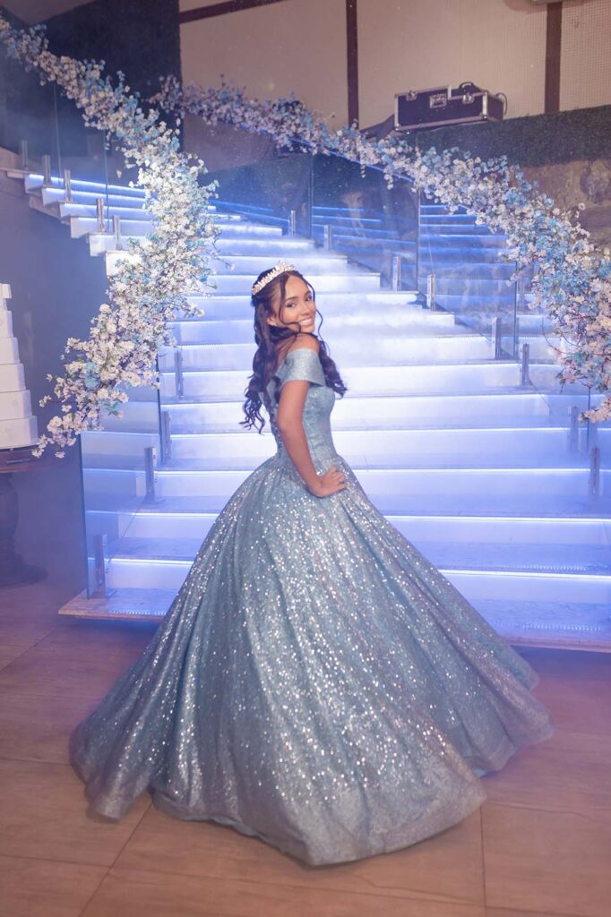 Debutante em vestido azul com a cauda estendida pelos degraus