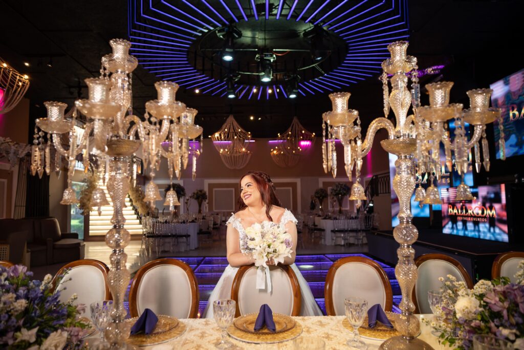 Noiva sentada à mesa dos noivos entre candelabros de cristal