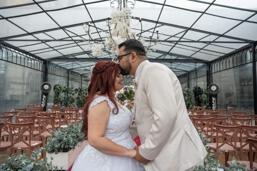 Noivos de mãos dadas diante do altar decorado com flores brancas