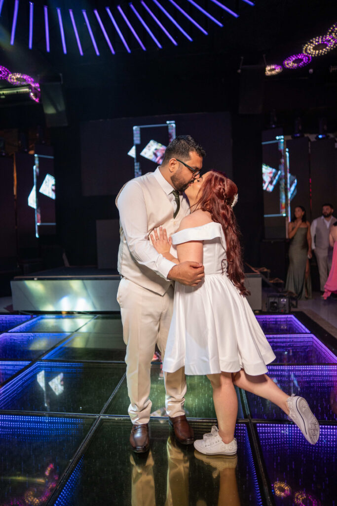 Noivos se beijam na pista de dança iluminada