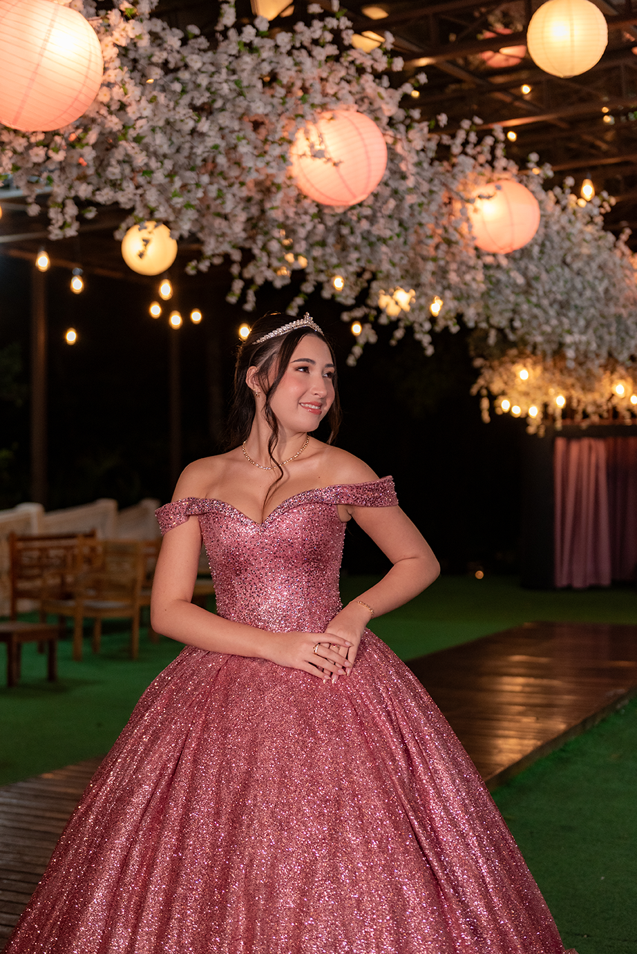 Debutante em vestido rosé na área externa sob lanternas de papel