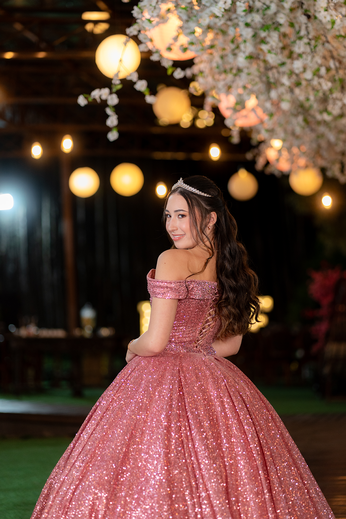Debutante em vestido rosé sob a decoração de flores brancas e lanternas