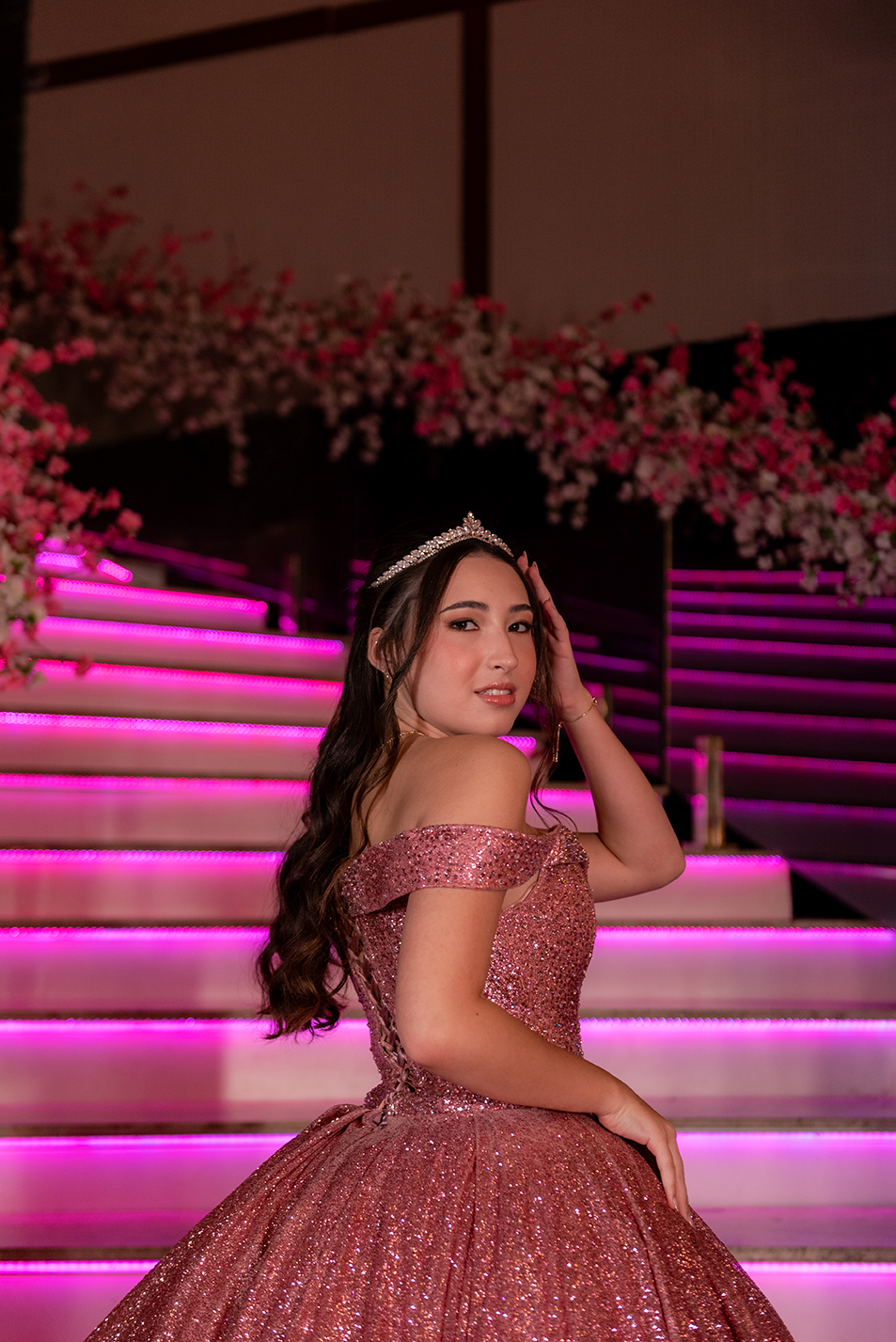 Debutante em vestido pink ao pé da escadaria iluminada da festa de 15 anos