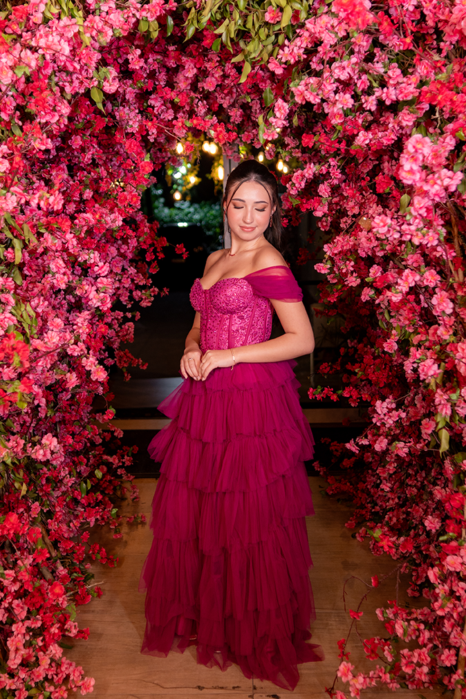 Debutante em vestido pink emoldurada pela parede de flores em tons de rosa