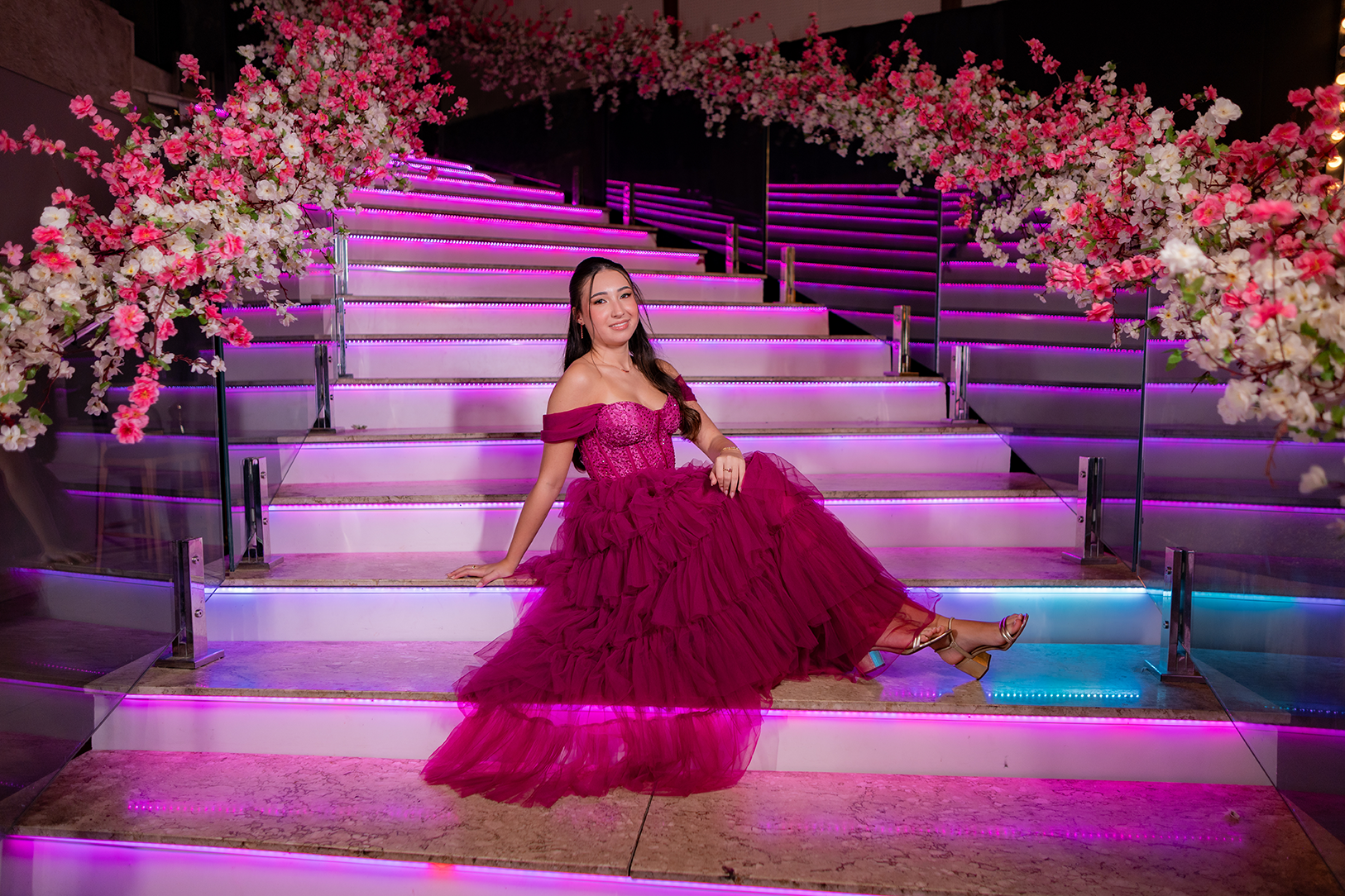 Debutante sentada na escadaria iluminada com o vestido pink estendido nos degraus