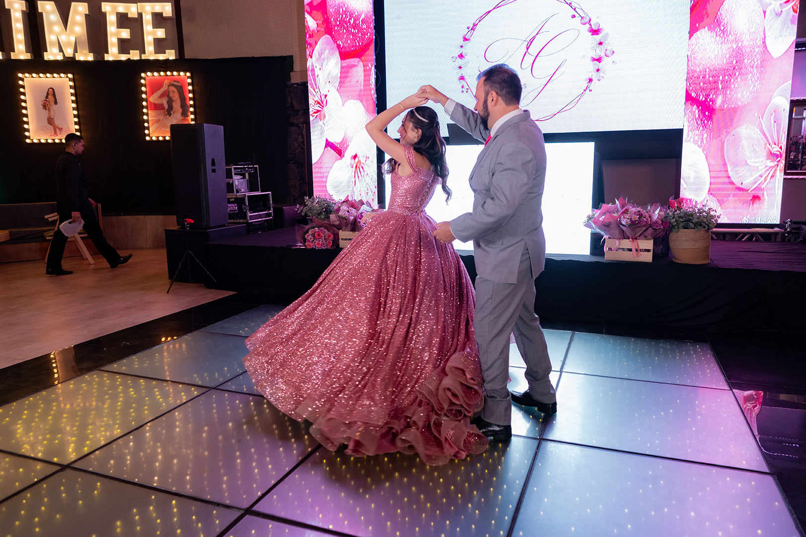 Debutante roda no vestido rosé durante a dança com o pai
