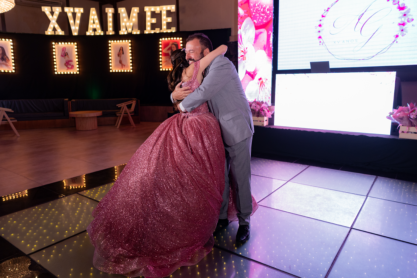 Debutante dança com o pai diante do letreiro luminoso XV Aimée