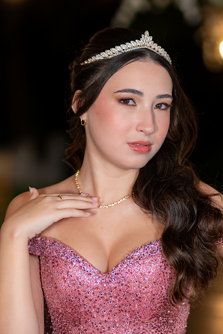Retrato aproximado da debutante com tiara e vestido rosé bordado em cristais