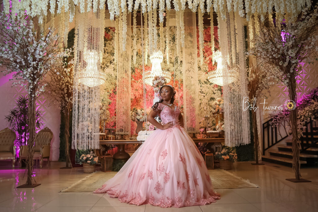 Debutante em vestido rosa no cenário decorado com flores e lustres