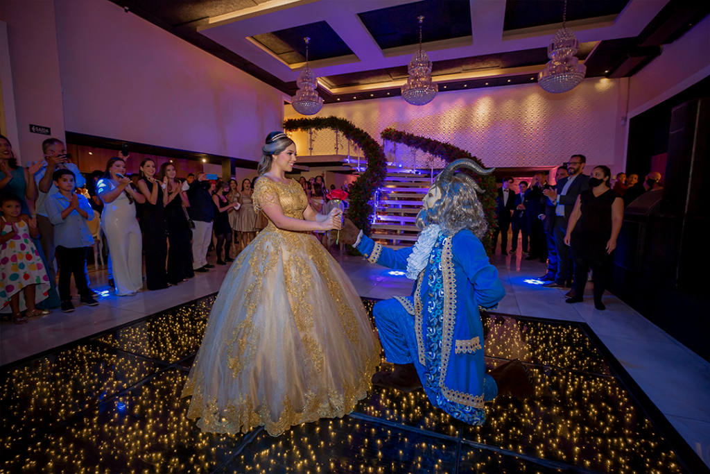 Debutante dança com personagem fantasiado no salão iluminado
