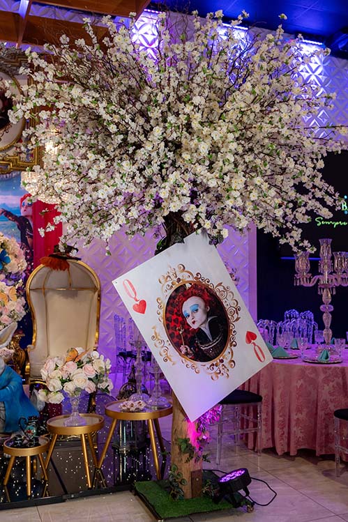Cenário com carta de baralho gigante, flores e cadeira dourada