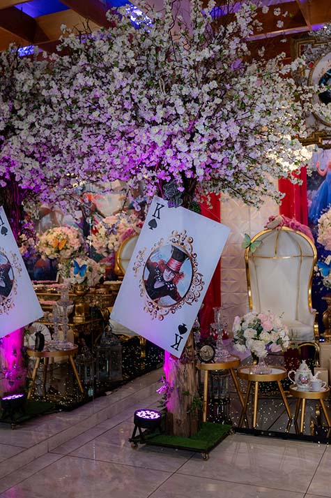Cenário com carta de baralho gigante e arranjos de flores brancas