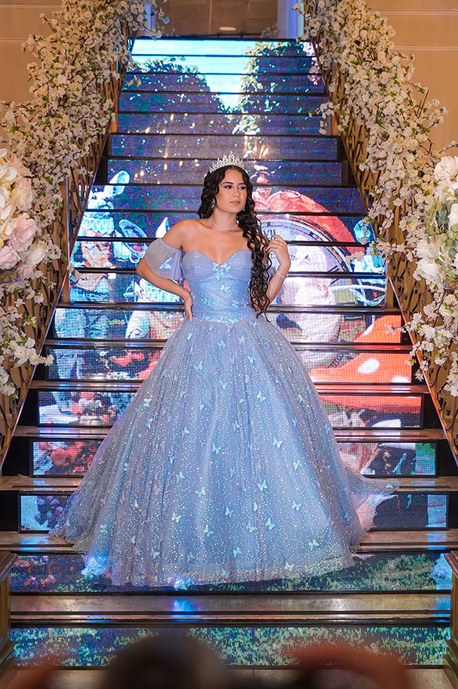 Debutante em vestido azul na escadaria de degraus iluminados