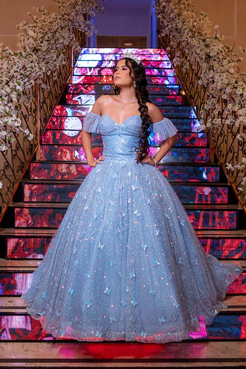 Debutante em vestido azul na escadaria de degraus coloridos
