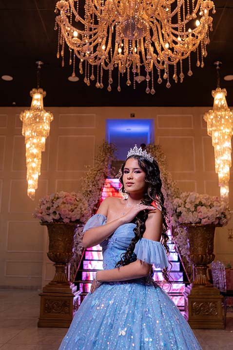 Debutante em vestido azul sob o lustre de cristal do salão