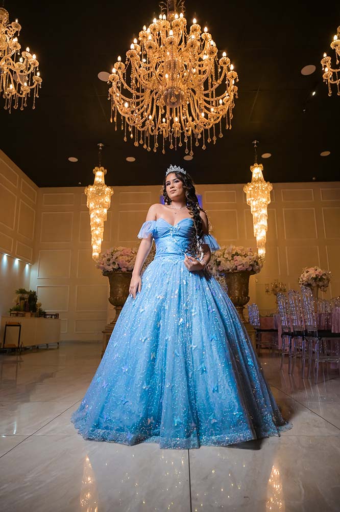 Debutante em vestido azul no salão sob os lustres de cristal