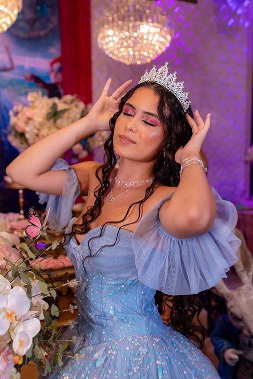 Retrato da debutante com coroa e vestido azul entre as flores