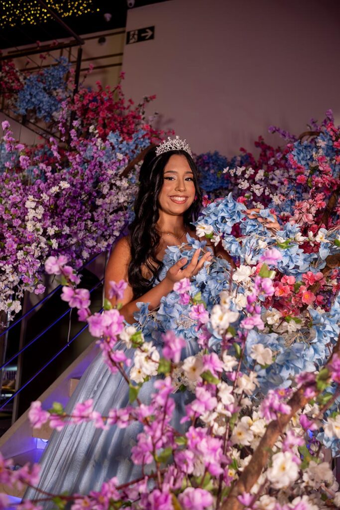 Debutante emoldurada pelas flores da decoração da festa de 15 anos