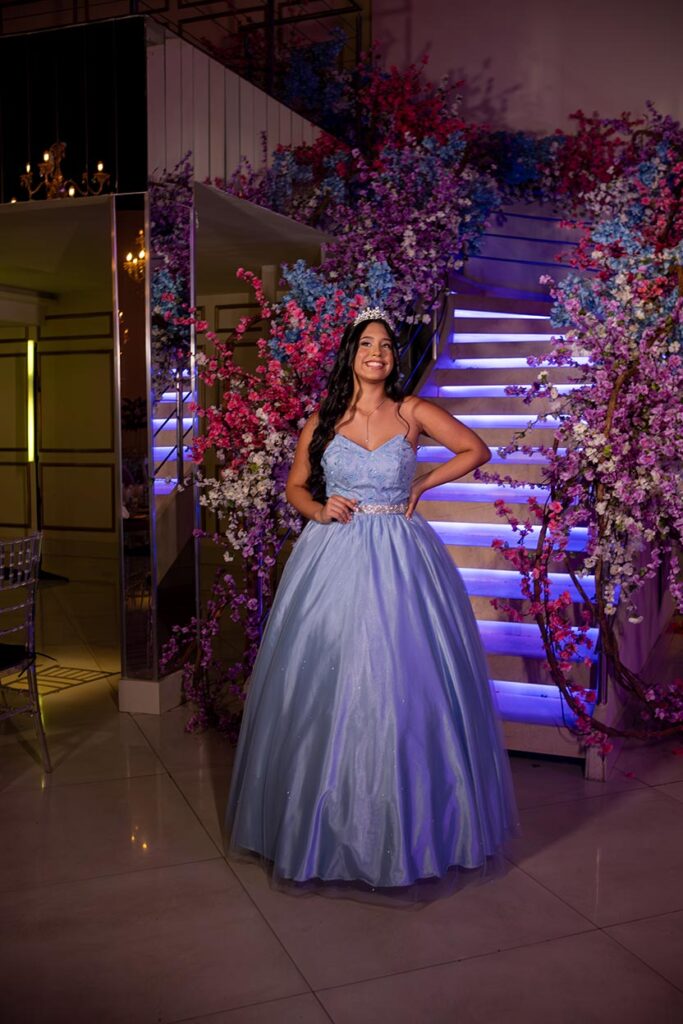 Debutante em vestido azul diante da escadaria iluminada