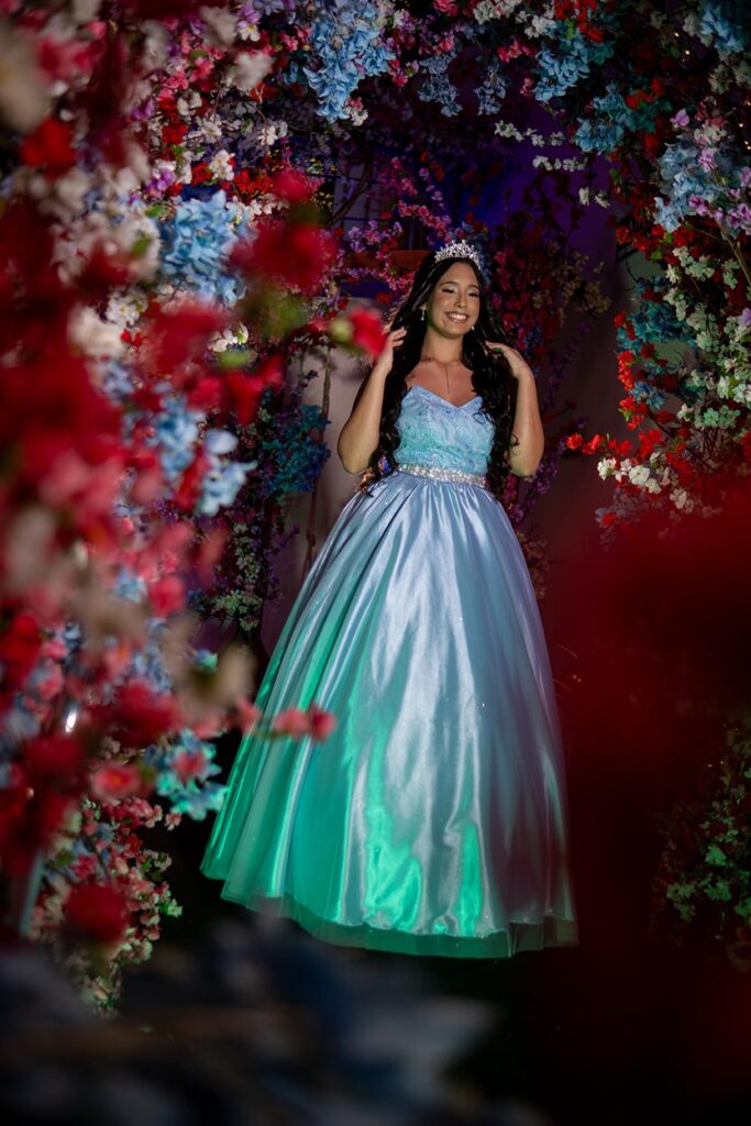 Debutante entre arranjos de flores em tons de vermelho e rosa