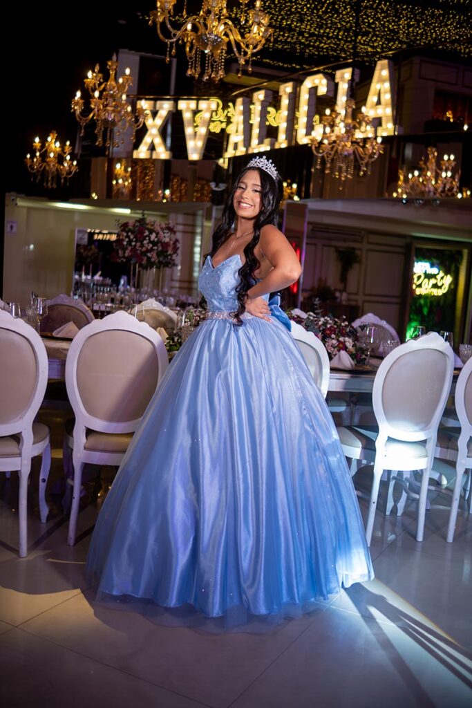 Debutante em vestido azul diante do letreiro luminoso e das mesas