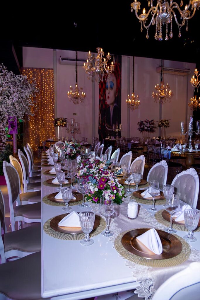 Mesa dos convidados com sousplats dourados e arranjo de flores
