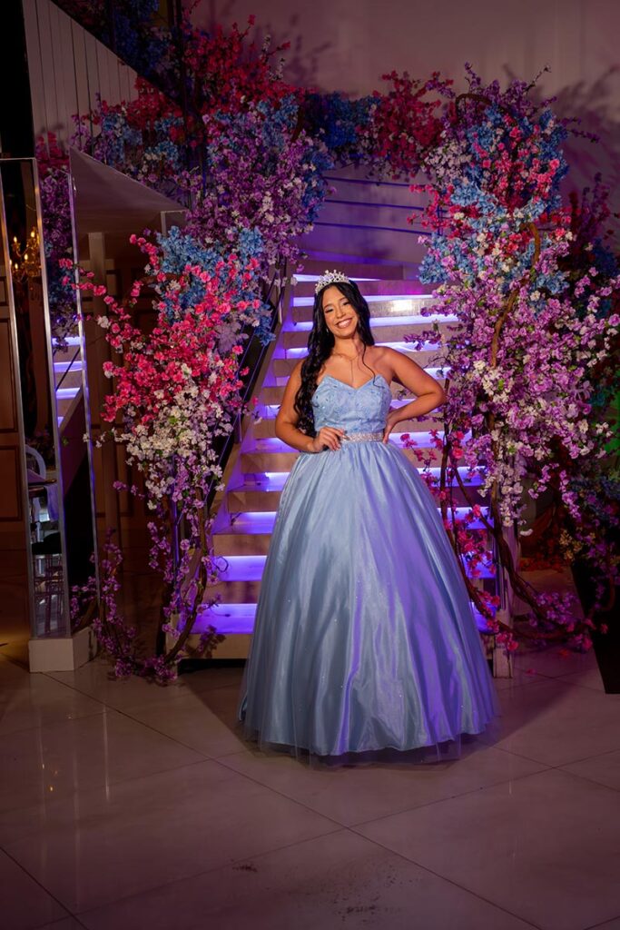 Debutante em vestido azul ao lado da escadaria decorada