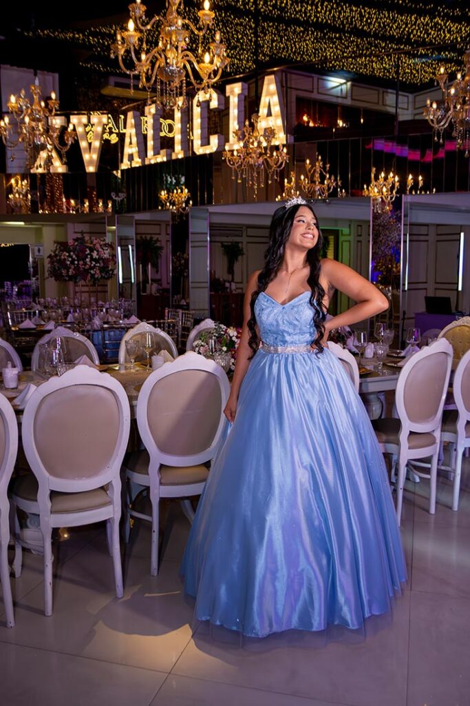 Debutante diante do letreiro luminoso e das mesas dos convidados