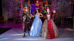 Debutante entre o Chapeleiro Maluco e a Rainha de Copas na pista da festa
