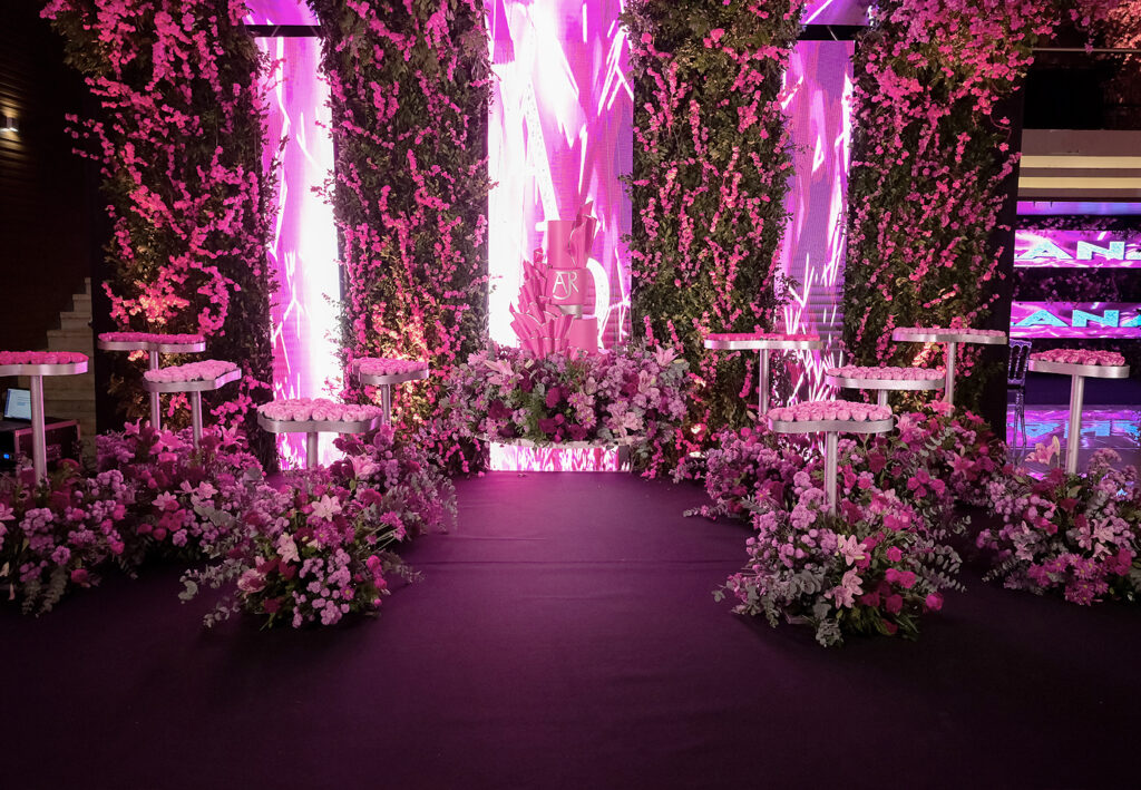 Salão com corredor de flores em tons de rosa e iluminação cênica