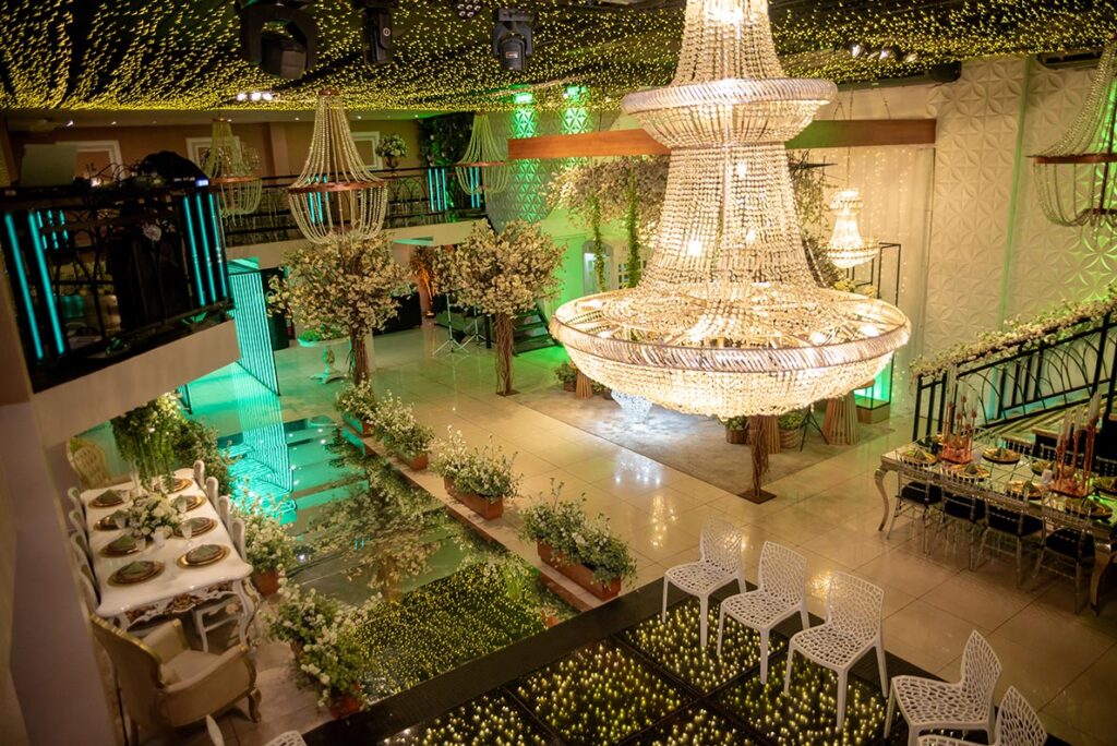 Salão de casamento com lustre de cristal e decoração em verde