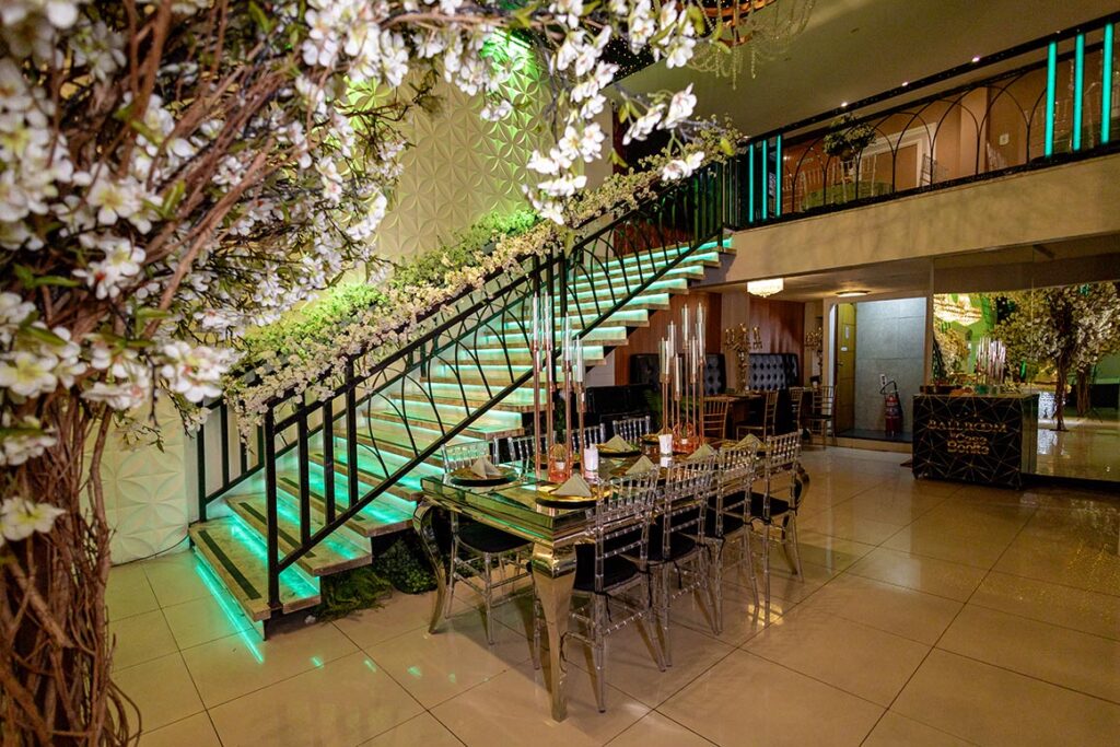 Escadaria do salão iluminada em verde com árvores decorativas