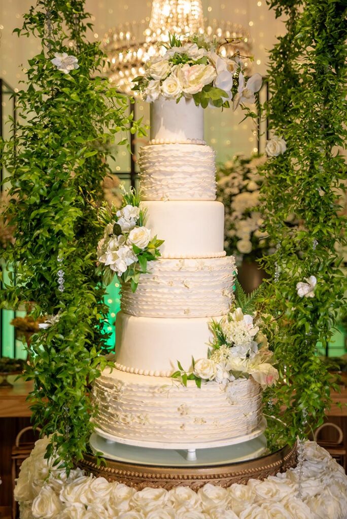 Bolo de casamento branco de vários andares cercado por flores