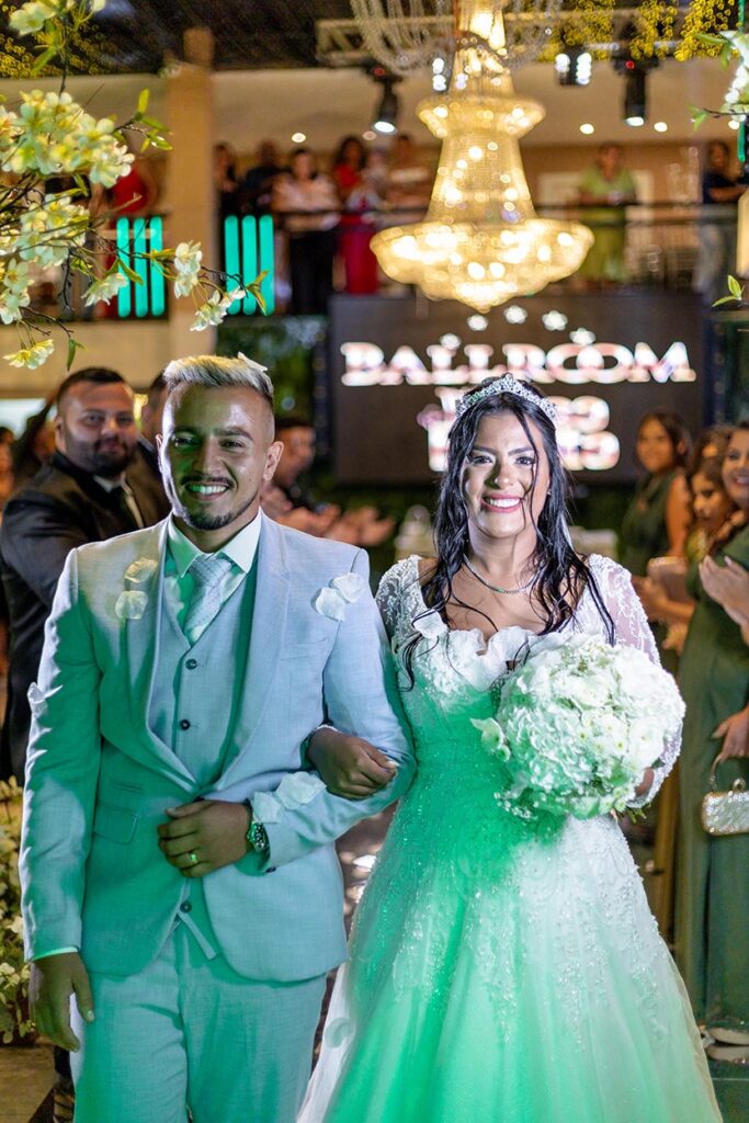 Casal de convidados posa diante do letreiro da casa de festas
