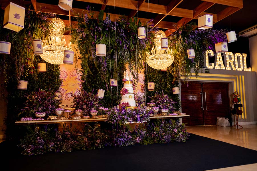 Mesa do bolo decorada com flores, folhagens e letreiro luminoso