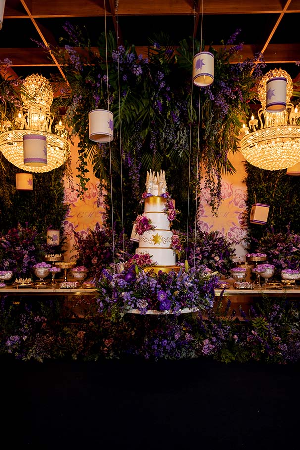 Mesa do bolo com flores e luminárias suspensas
