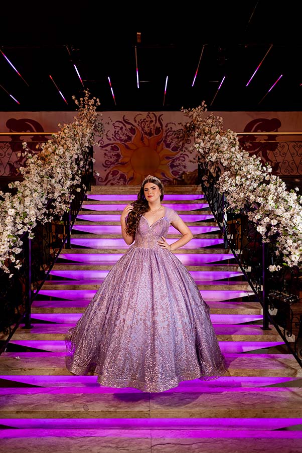 Debutante no centro da escadaria iluminada decorada com flores brancas