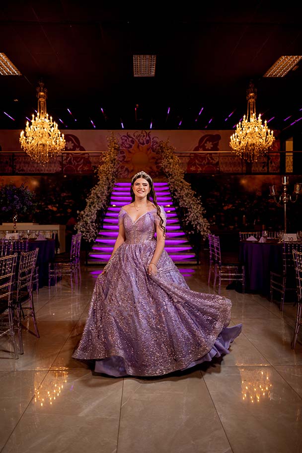 Debutante em vestido lilás no salão com lustres de cristal
