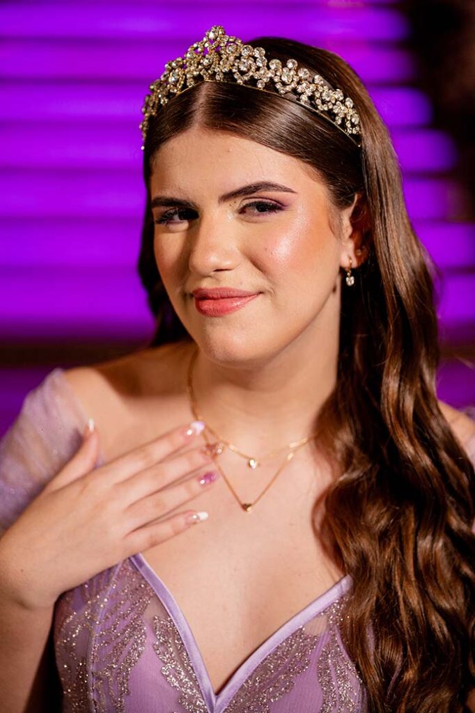 Retrato aproximado da debutante com tiara diante da escadaria iluminada