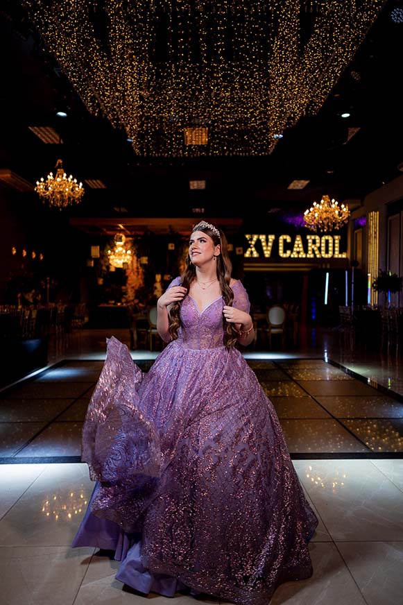 Carolina em vestido lilás diante do letreiro luminoso com seu nome