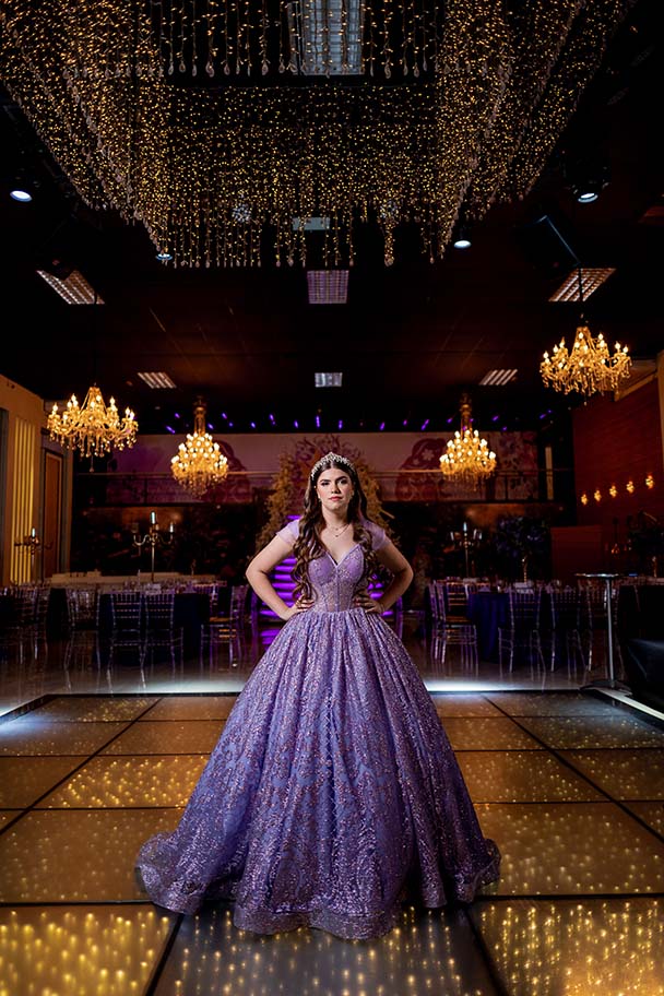 Debutante em vestido lilás na pista iluminada do salão