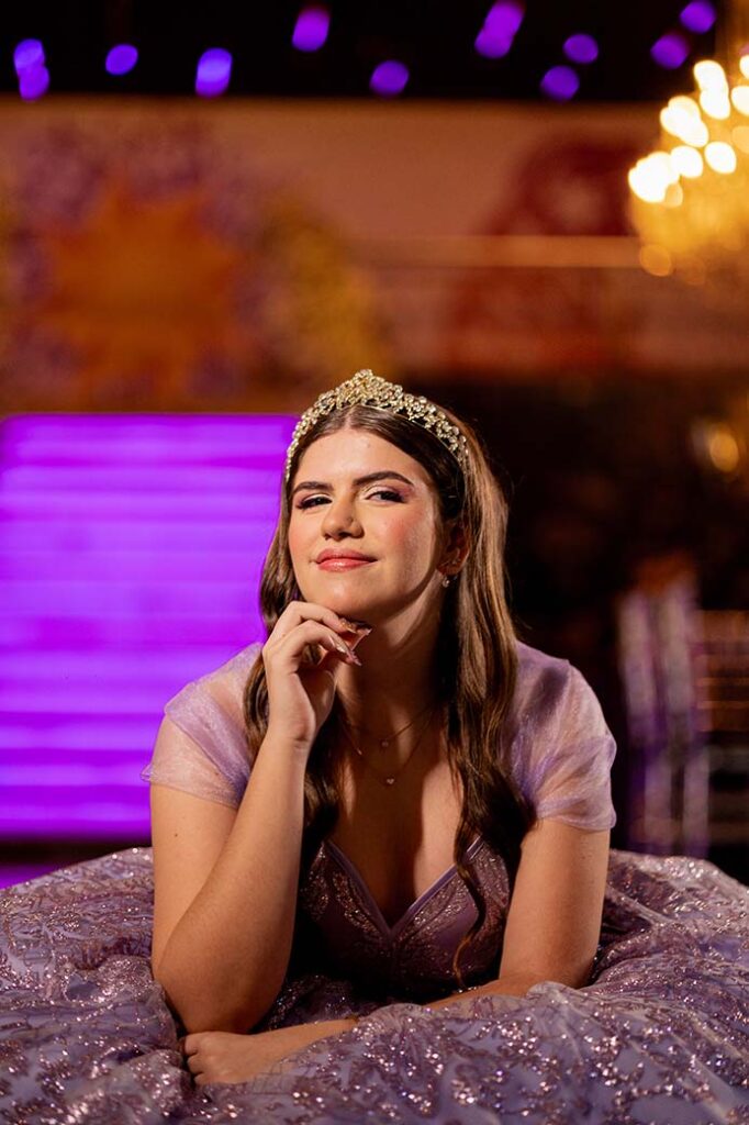 Debutante sentada nos degraus com o vestido lilás estendido