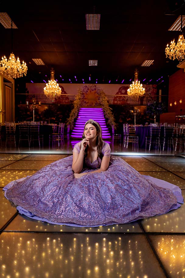Debutante sentada na pista iluminada com o vestido espalhado ao redor