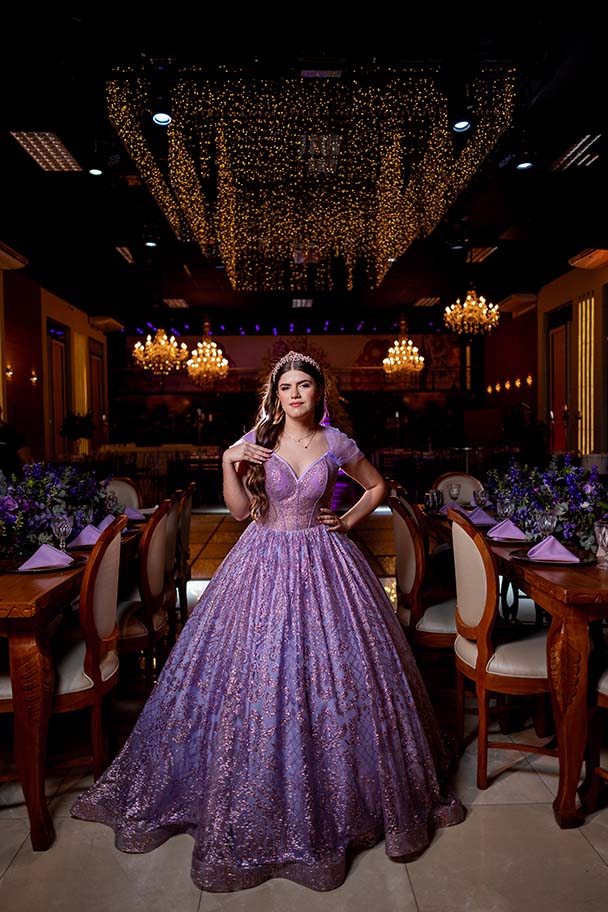 Debutante em vestido lilás entre as mesas do salão